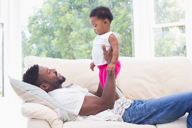 Padre feliz con la niña en el sofá