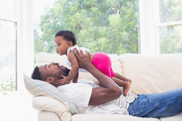 Padre feliz con la niña en el sofá