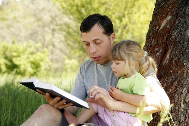 Padre feliz con un niño leyendo un libro sobre la naturaleza de la Biblia