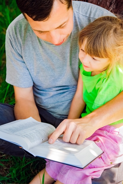 Padre feliz con un niño leyendo un libro sobre la naturaleza de la Biblia