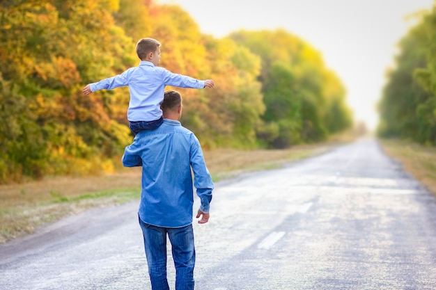 Un padre feliz con un niño en el parque con las manos en los viajes por la naturaleza van por la carretera