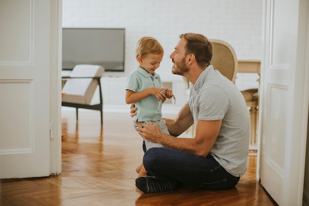 Foto padre feliz y pequeño hijo jugando y divirtiéndose en casa