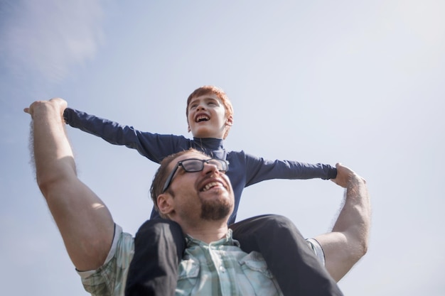 Foto padre feliz sostiene a su hijo sobre sus hombros el concepto de paternidad