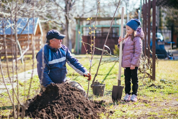 Padre feliz con su hija plantando un árbol frutal