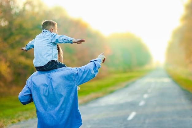 Un padre feliz con su hijo está caminando por la carretera en el parque en viajes por la naturaleza