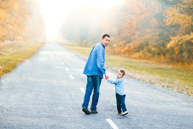 Un padre feliz con su hijo está caminando por la carretera en el parque en viajes por la naturaleza