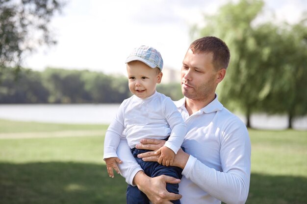 Padre feliz con su hijo pequeño parado en un parque soleado