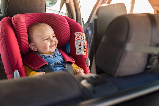 Foto padre fija a su bebé en el asiento del coche