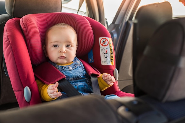 Foto padre fija a su bebé en el asiento del coche