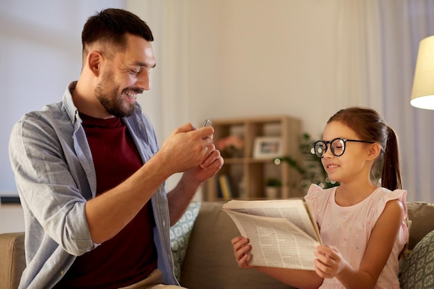 Foto padre fotografiando a su hija por teléfono móvil en casa