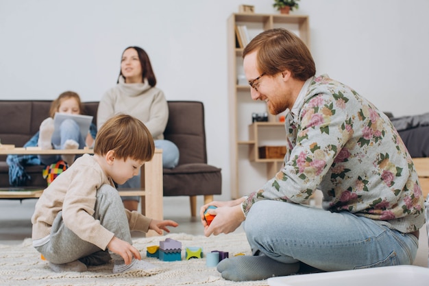 Foto padre en gafas e hijo adorable del niño que construye la torre de madera del constructor.