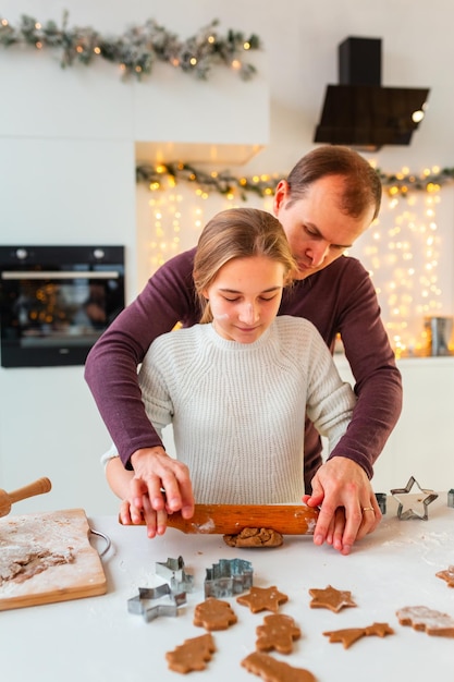 Padre con hija cocinando haciendo pan de jengibre, cortando galletas de masa de jengibre, divirtiéndose.