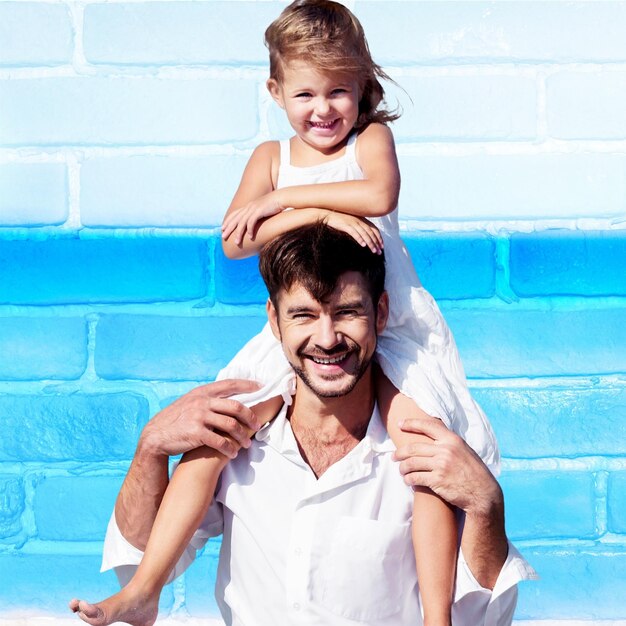 Padre con hija a cuestas sobre fondo de pared