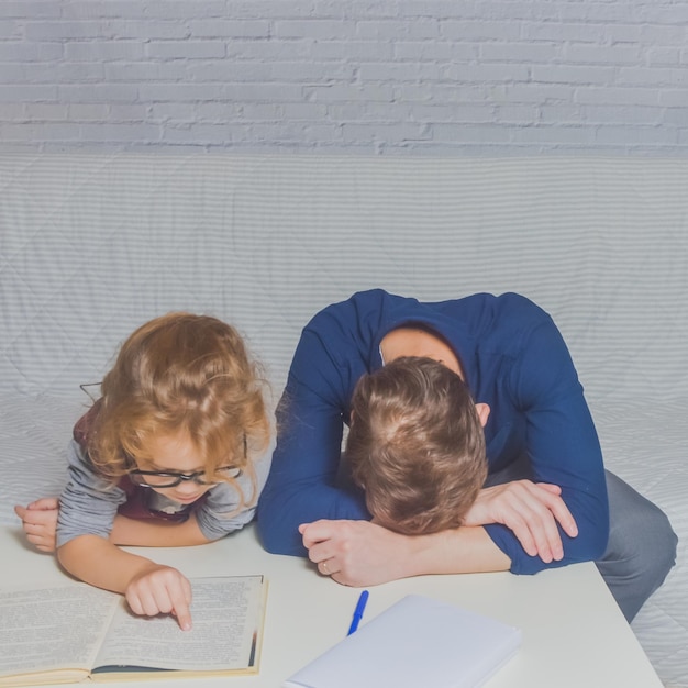 El padre y la hija hacen la tarea después de la escuela primaria.