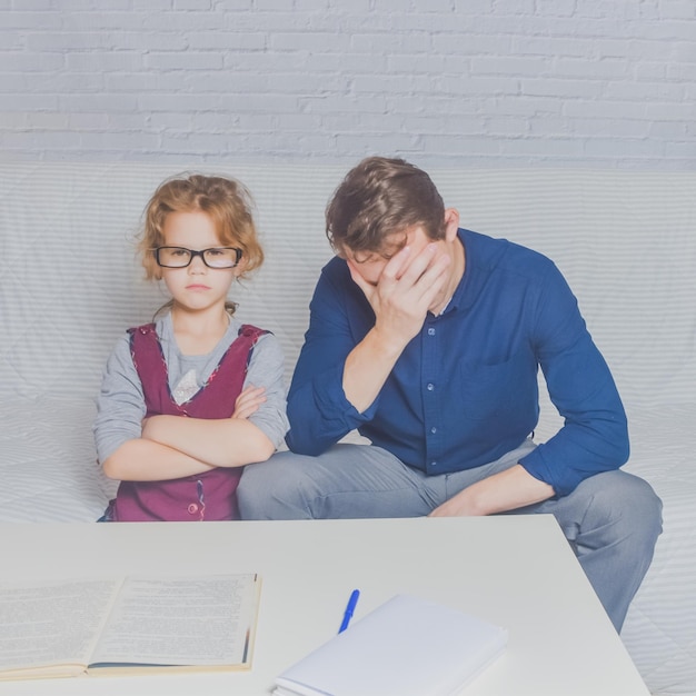 El padre y la hija hacen la tarea después de la escuela primaria.