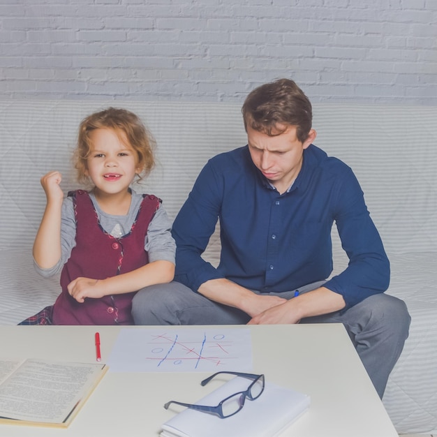 El padre y la hija hacen la tarea después de la escuela primaria.