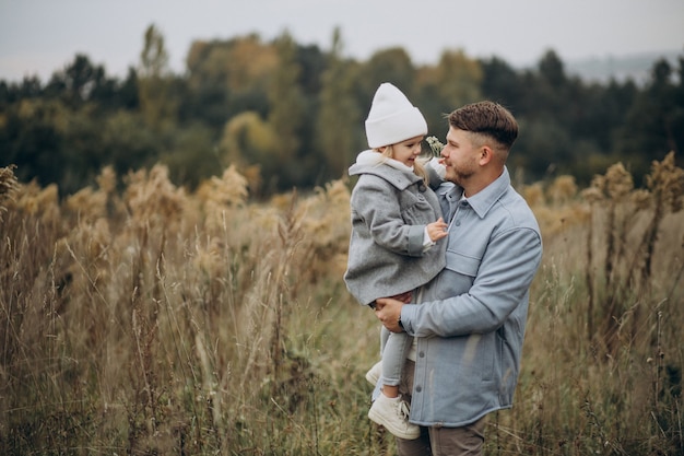 Padre con hija pequeña juntos en clima otoñal divirtiéndose