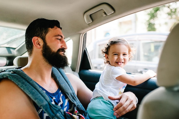 Padre con una hija pequeña sentada en un automóvil en las calles de la ciudad de Tbilisi, en la capital de Georgia, en el soleado día de primavera. Papá y niña viajan de excursión en el casco antiguo.