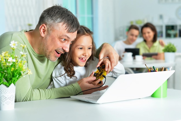 Foto padre con una hija pequeña usando una laptop jugando