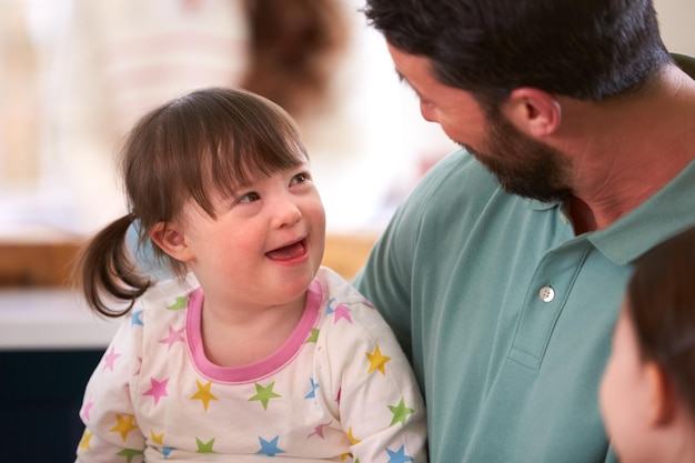 Padre con hija con síndrome de Down sentados alrededor de una mesa en casa