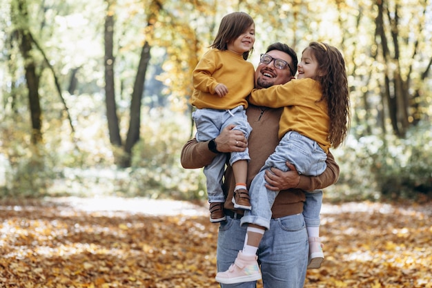 Padre con hijas divirtiéndose en el parque otoñal