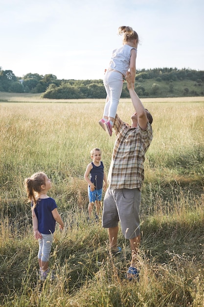 Foto padre con hijas e hijo en tierra durante un picnic