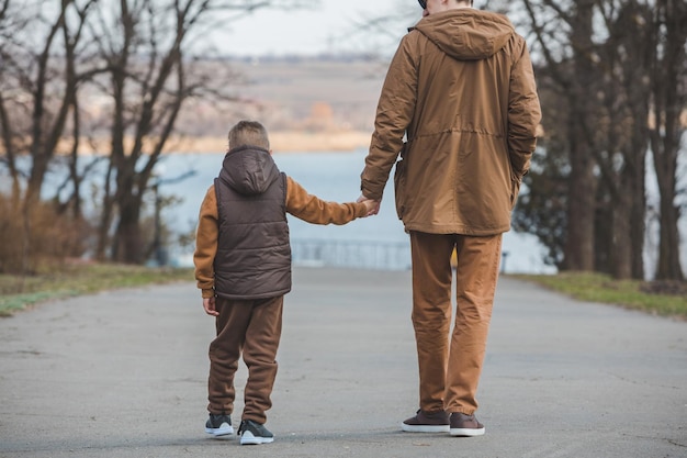 Padre con hijo caminando por el parque cogidos de la mano