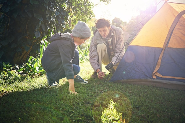 Padre hijo y carpa de martillo para acampar al aire libre en la naturaleza de vacaciones uniéndose y puesta de sol Papá chico y preparando el aprendizaje del campamento y ayudando en el bosque para la educación y la aventura de viajes