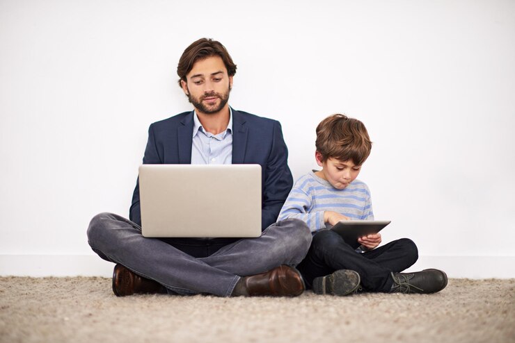 Foto padre y hijo con computadora portátil en el suelo para aprender educación en línea y relajarse en casa niño padre y computadora para estudiar en internet y familia leyendo información sobre tecnología juntos por la pared