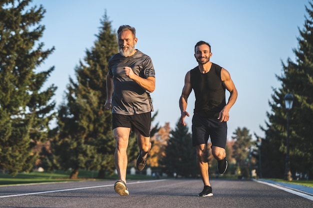 Foto el padre y un hijo corriendo por la carretera del parque.