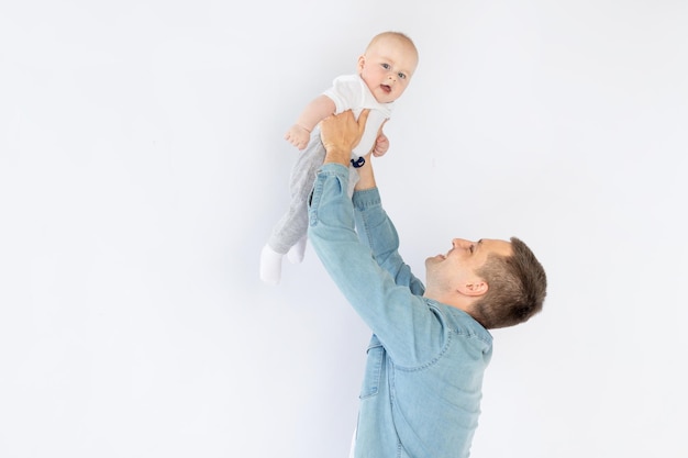 Un padre con un hijo pequeño sobre un fondo blanco aislado y vacío en un estudio fotográfico jugando a abrazar Paternidad feliz o familia