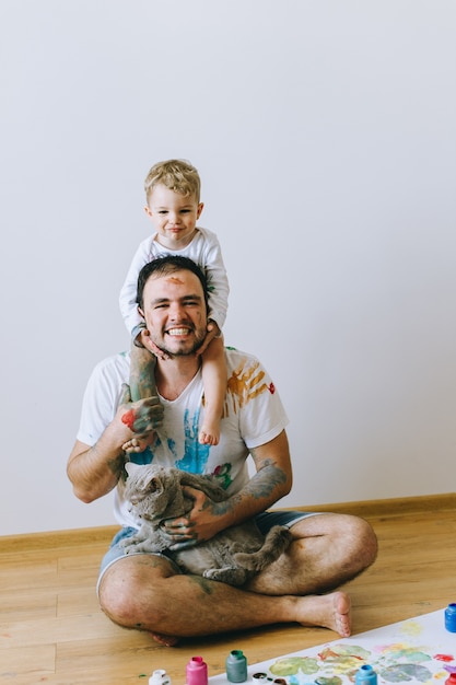 padre con un hijo sobre sus hombros y un gato en sus manos pintado con pintura