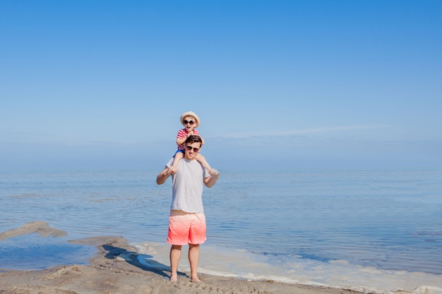 Padre con hijo sobre sus hombros en la playa.