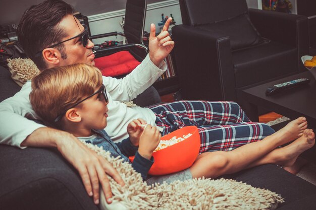 Foto padre con hijo viendo la televisión mientras está sentado en el sofá en casa