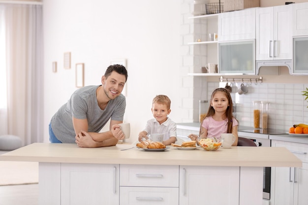 Padre con hijos desayunando en la cocina