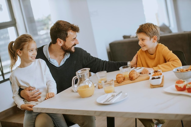 Padre joven desayunando con su hijo e hija en casa