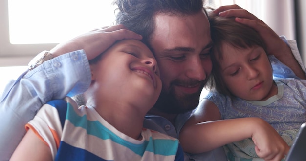 Foto padre joven con dos hijos usando tecnología en apartamento moderno