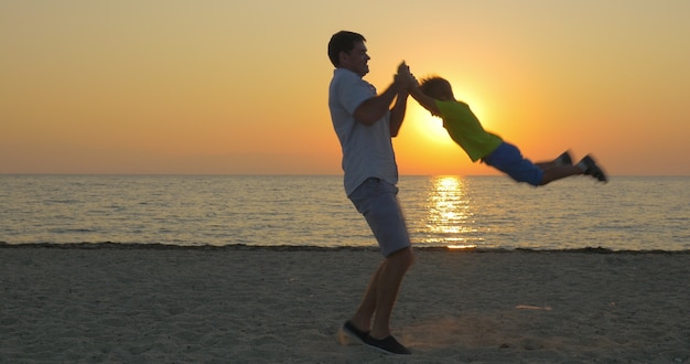 Padre joven e hijo pequeño divirtiéndose en la playa