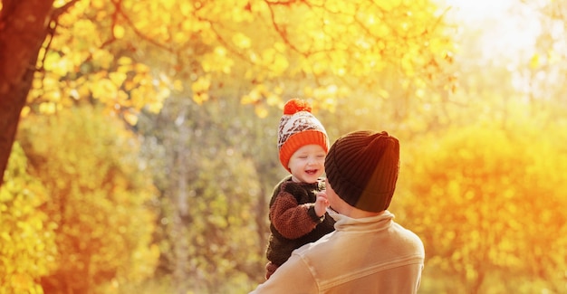 Padre joven e hijo pequeño en el parque otoño