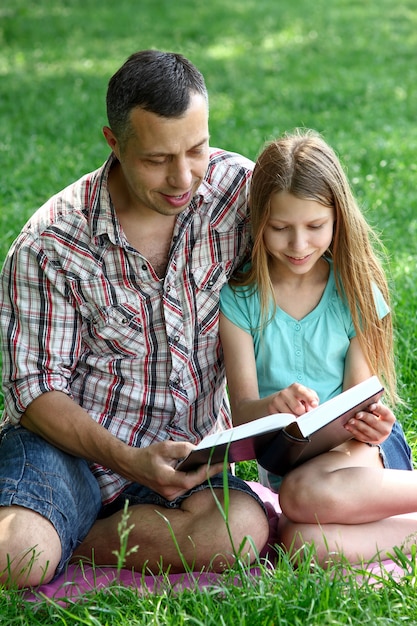 Padre joven feliz con una hija leyendo la Biblia