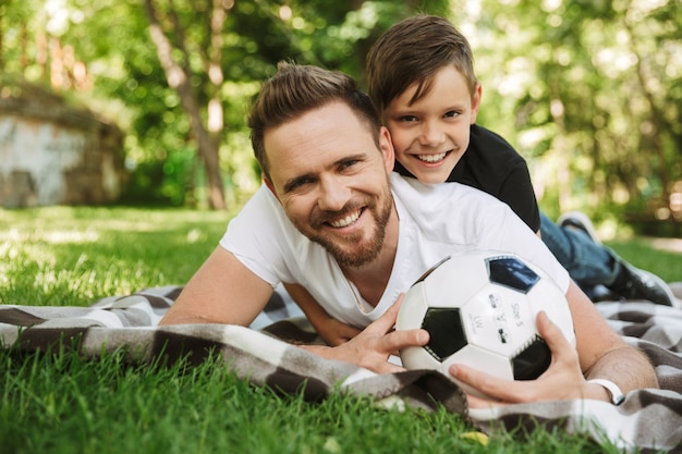 Padre joven feliz con su pequeño hijo con fútbol