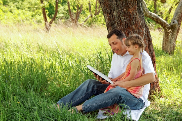 Padre joven con una hija pequeña leyendo la Biblia