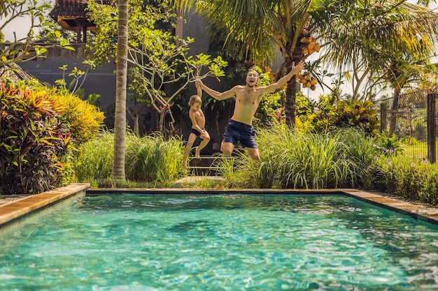 Padre joven con hijo pequeño jugando en la piscina.