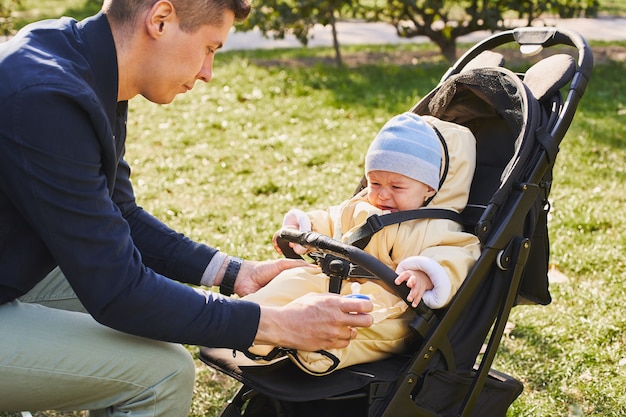 Un padre joven en un paseo por un parque de otoño con un hijo pequeño