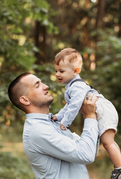 Un padre joven con su hijo pequeño en la naturaleza en el verano. Abrazos y besos