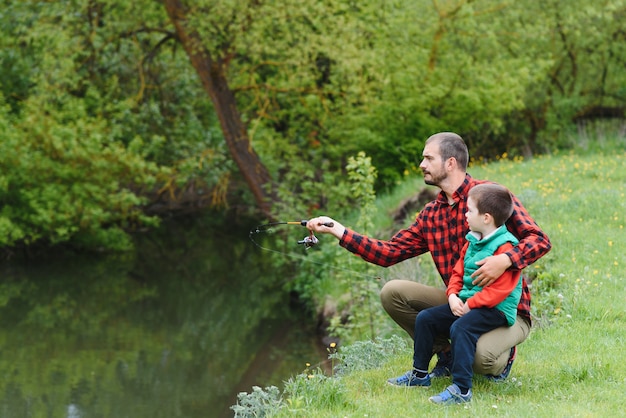 Padre joven y su hijo pescando en la naturaleza.