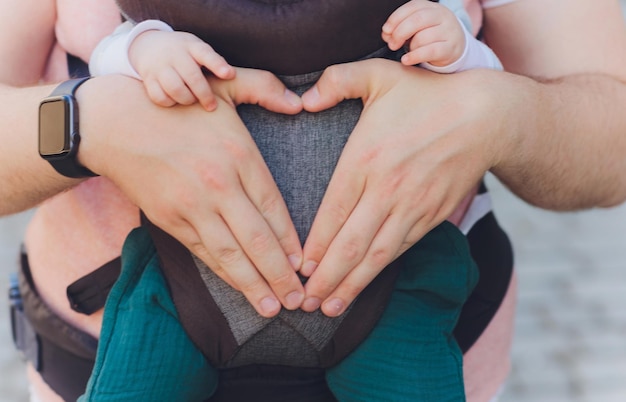 Padre joven y su niña en un portabebés