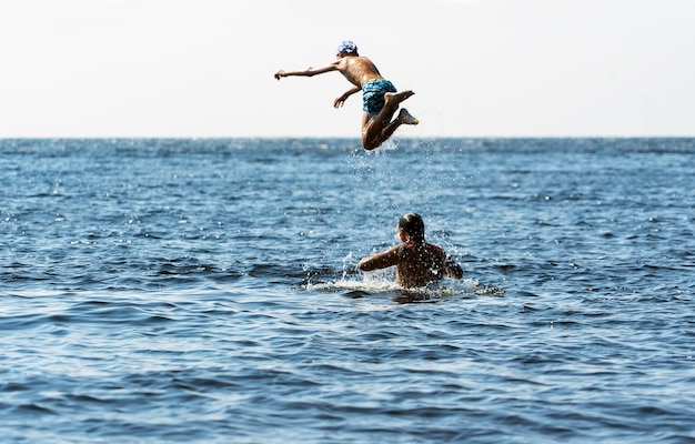 Un padre joven tira a su hijo de sus hombros al agua en el lago Ladoga