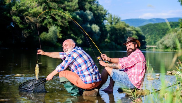 Padre jubilado e hijo maduro con barba, pesca deportiva, relajarse en la naturaleza, pescar con mosca, pasatiempo de los hombres, pesca de retiro, amistad de pescadores felices, dos amigos pescando juntos, buen día para pescar.