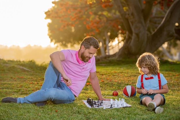 Foto padre juega al ajedrez con su hijo escuela de ajedrez para niños juego exterior familiar